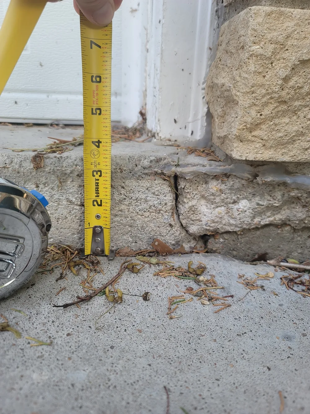 Measuring a 7-inch drop in a sunken concrete step during a Concrete Rescue assessment